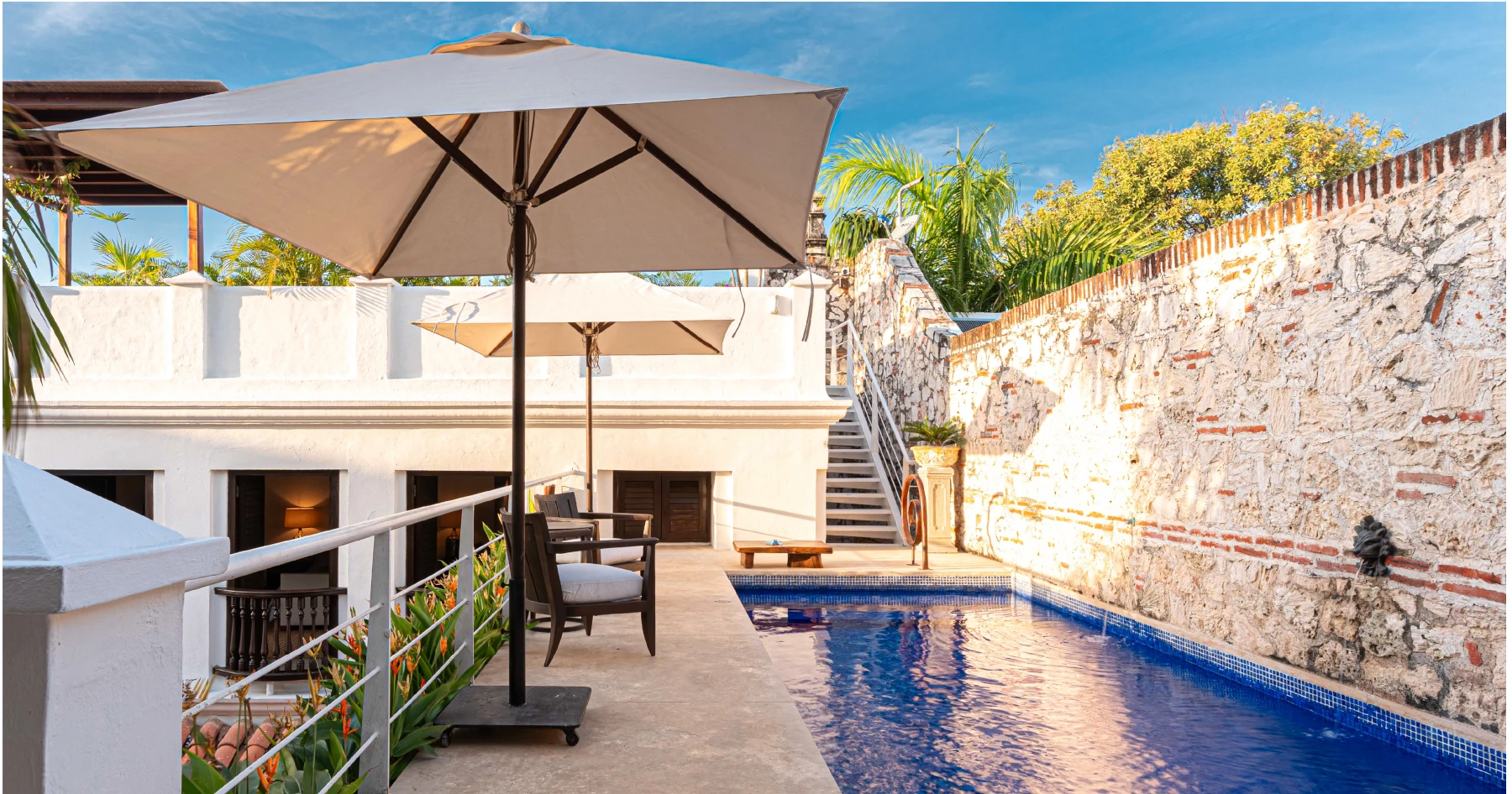 Baño de concepto abierto con acabados artesanales, lavabos de diseño y vistas a la zona de piscina privada
