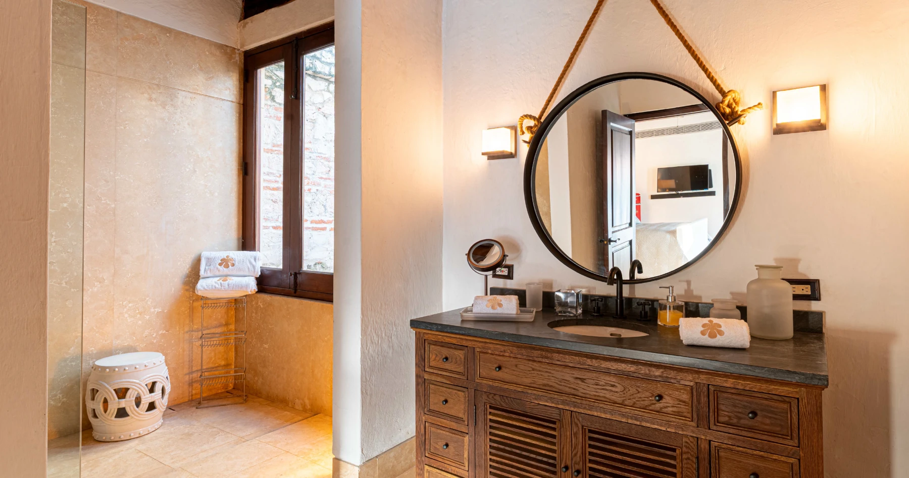 Baño moderno tipo suite con encimera de madera, lavabos artesanales sobrepuestos y espejos circulares con iluminación integrada