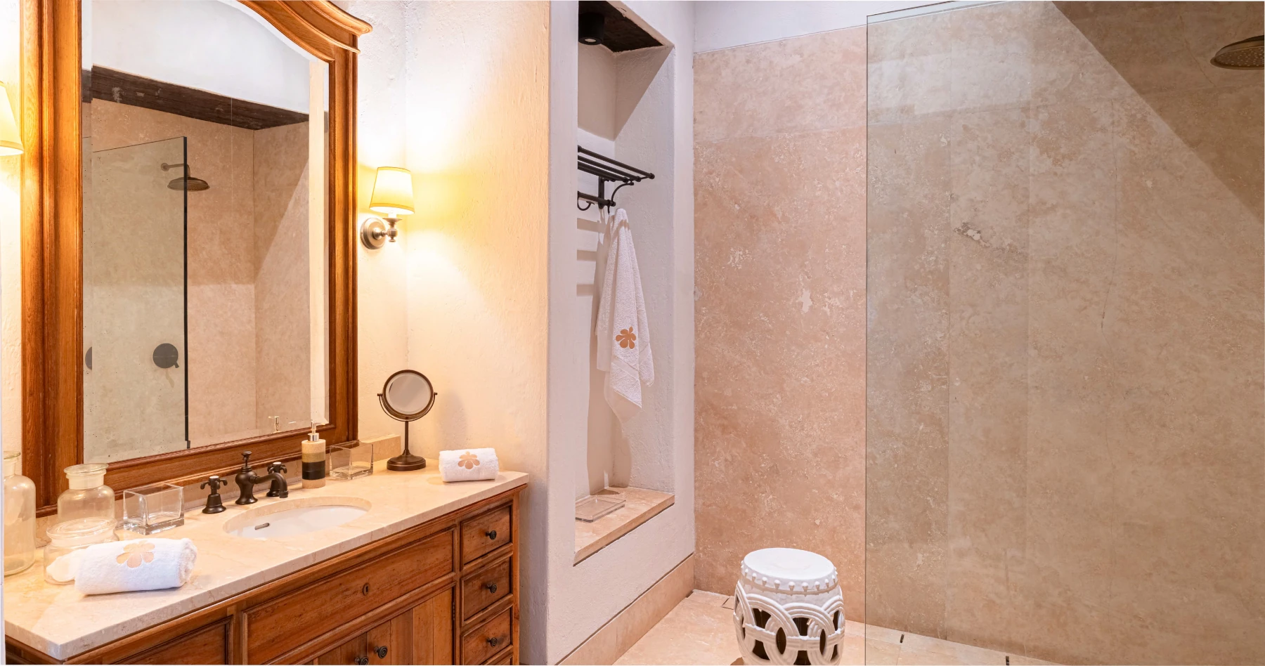 Baño principal de la suite Coral con lavamanos de piedra natural, espejos circulares retroiluminados y acabados en mármol de alta gama