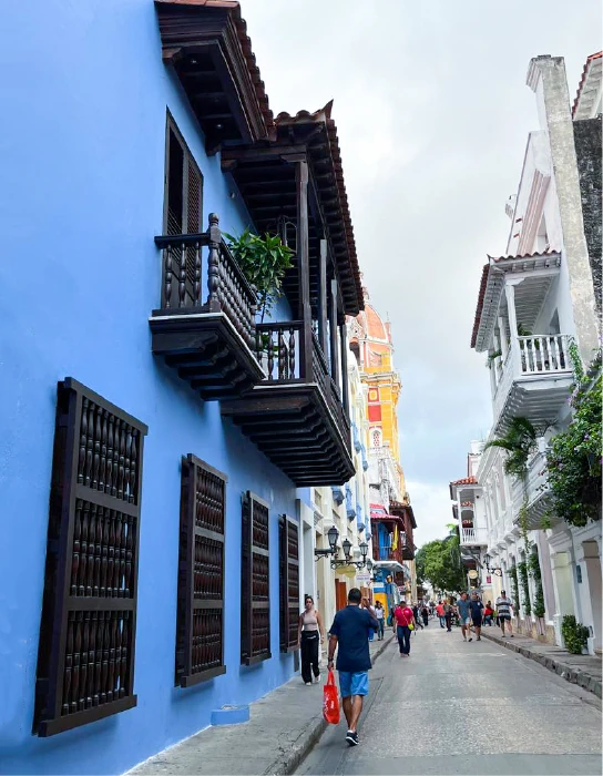 Calle turística actual de Cartagena con fachadas de colores vibrantes y balcones coloniales de madera