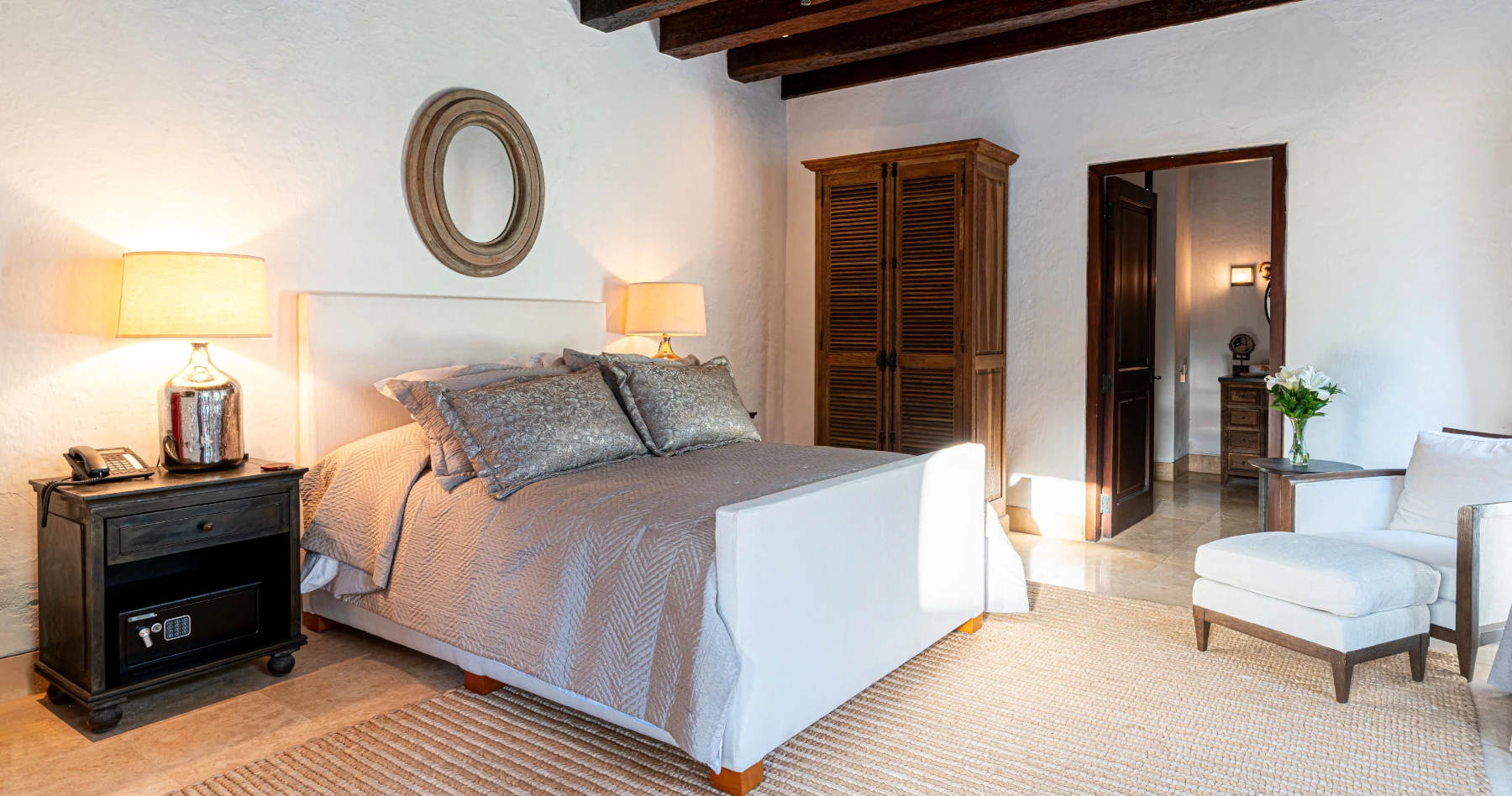 Dormitorio de lujo con cama King, textiles premium en tonos blancos y una atmósfera luminosa resaltada por techos altos de madera noble