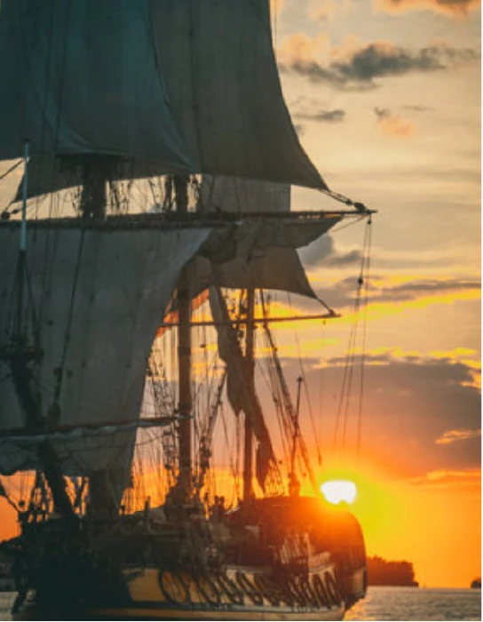 Velero antiguo navegando frente a las costas de Cartagena al atardecer, evocando la época colonial