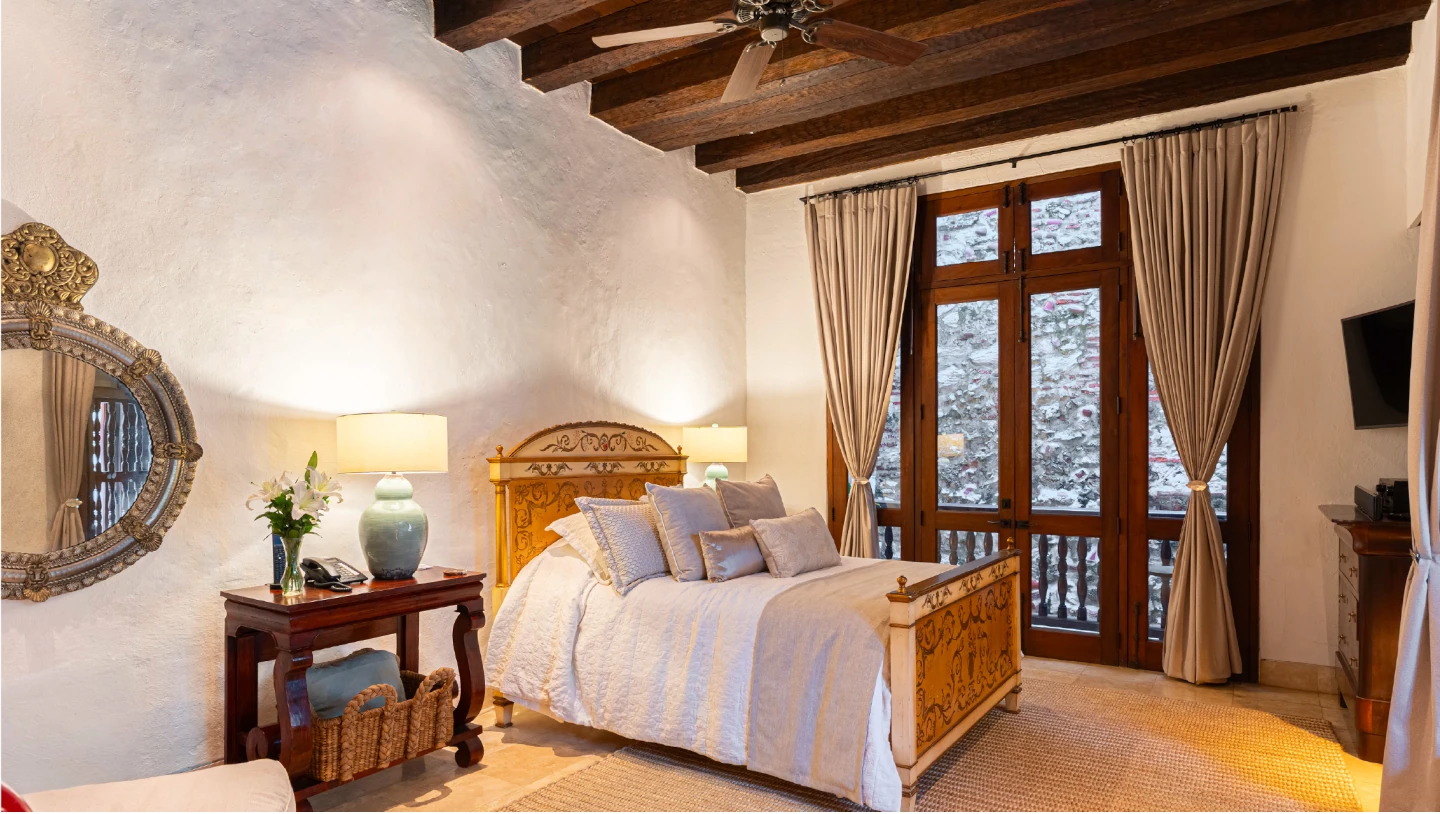 dormitorio boutique con decoración rústica elegante, vigas de madera y ventanales coloniales